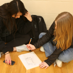 Two partners examine a paper with a diagram of a vehicle.